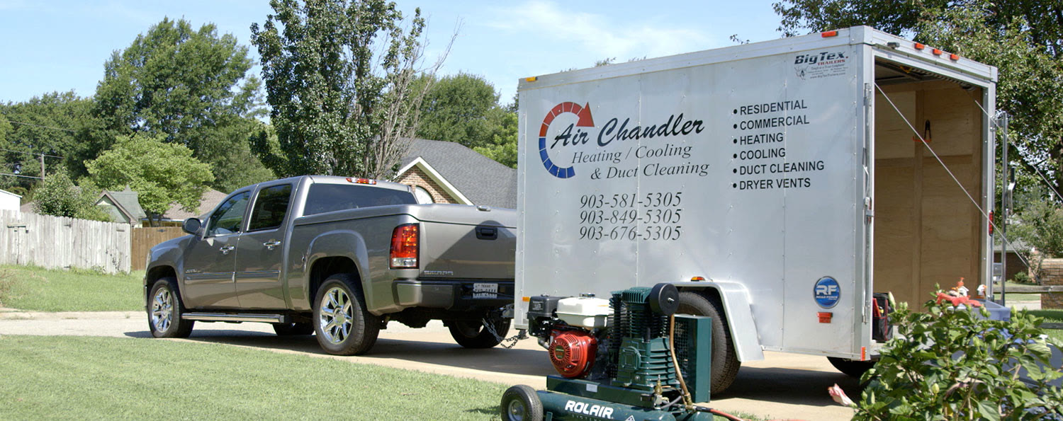 An Air Chandler trailer and pickup parked on a lawn-lined street